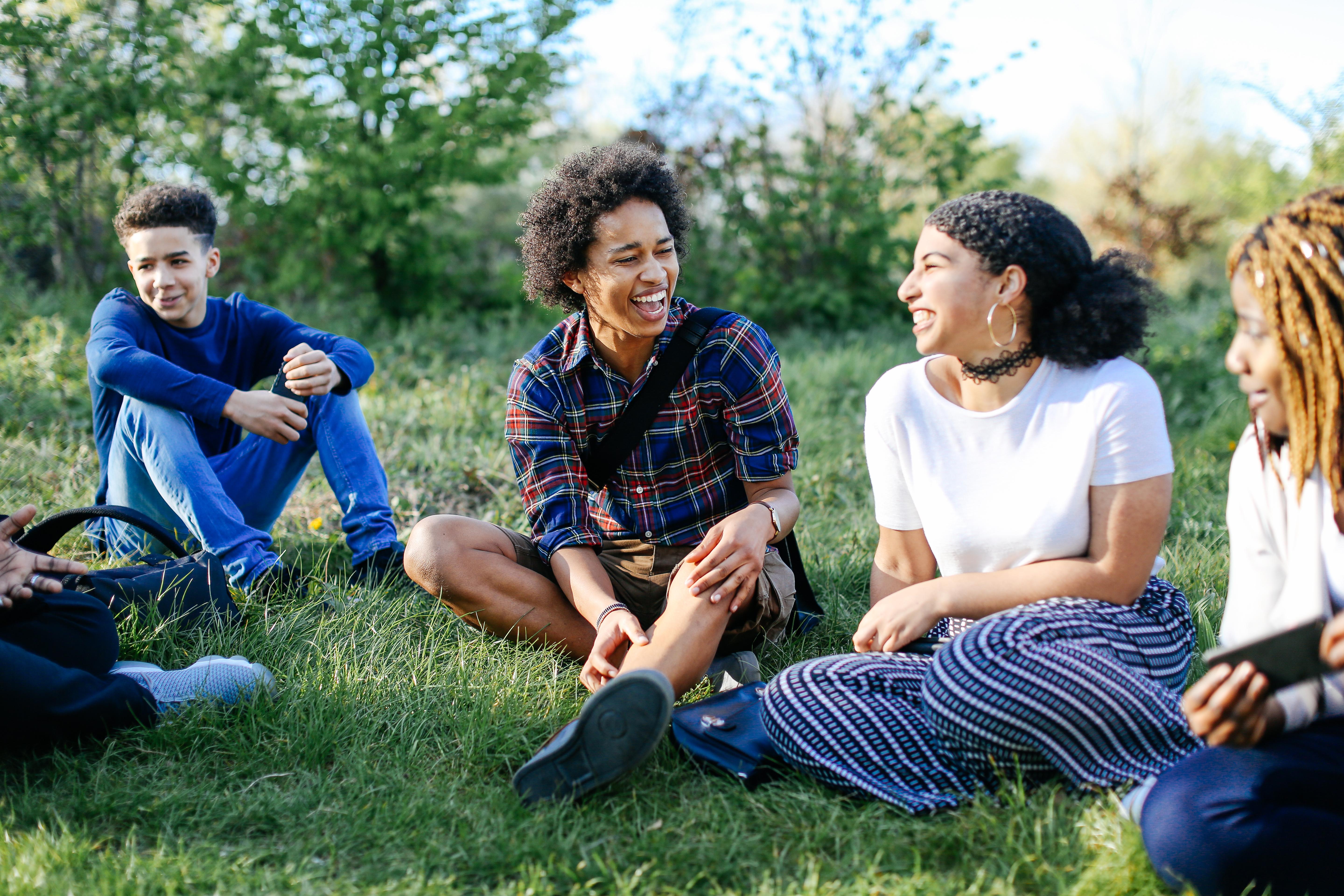 group of teens smiling and hanging out in nature