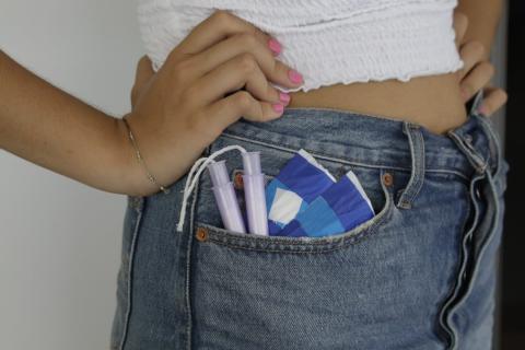 View of a woman's jean pocket filled with tampons and sanitary pads.